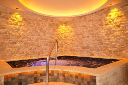 y baño con bañera y pared de piedra. en Emirtimes Hotel&Spa - Tuzla en Estambul