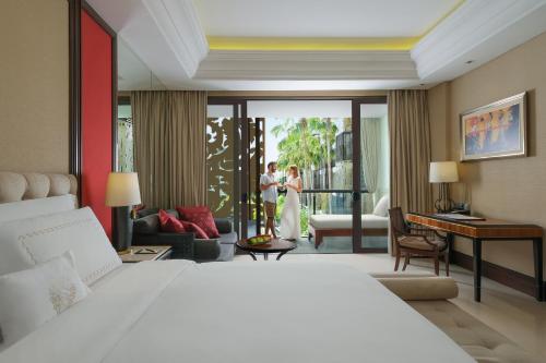 a bedroom with a bed and a couple standing on a balcony at The Trans Resort Bali in Seminyak