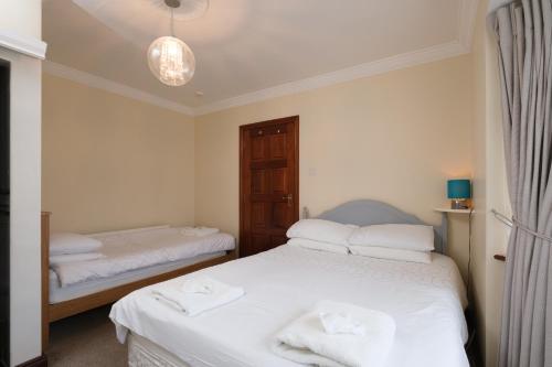 two beds in a room with white sheets and towels at Four Seasons B&B in Galway