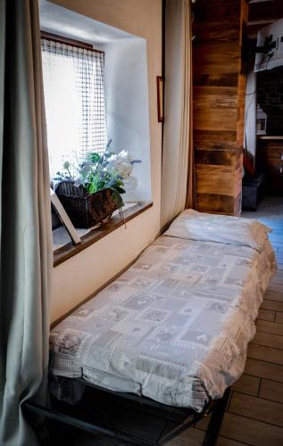 a small bed in a room with a window at Chalet in pietra e legno con caminetto in Inverso Pinasca