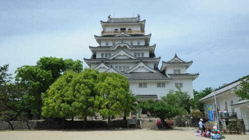 a large white building with a tree in front of it at Business Inn Fukuyama in Fukuyama