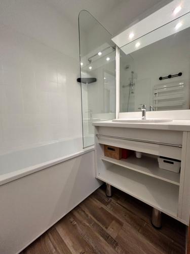 a white bathroom with a sink and a mirror at Chaleureux logement centre Valmeinier 1800 avec Piscine -Vue Montagne - 6 personnes in Valmeinier