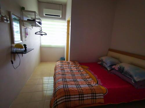 ein Schlafzimmer mit einem Bett mit einer roten Decke und einem Fenster in der Unterkunft Riqayraa Muslim Homestay in Seremban