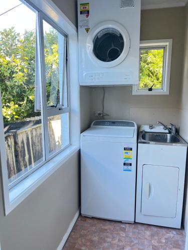 a laundry room with a washer and dryer and a window at Family suite at Campbells Bay -Netflix TV in Auckland