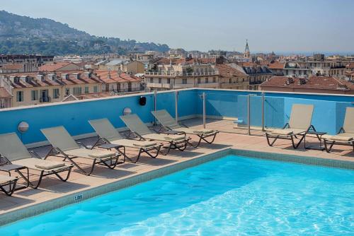 - une piscine avec des chaises et une vue sur la ville dans l'établissement NH Nice, à Nice