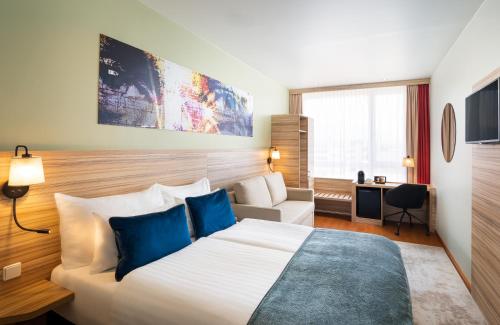 ザルツブルクにあるLeonardo Hotel Salzburg Airportの大きなベッドとソファが備わるホテルルームです。