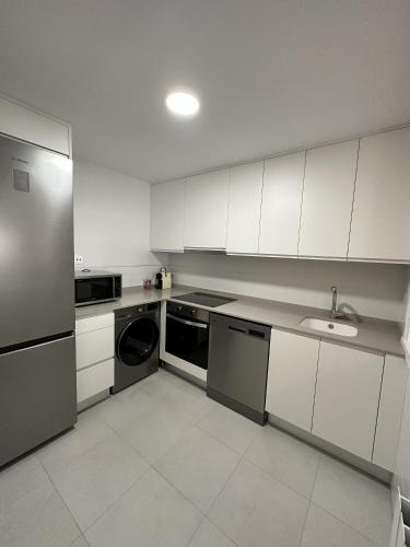 a white kitchen with a sink and a dishwasher at Apartamentos Encanto Mudéjar in Teruel