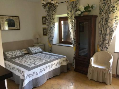 a bedroom with a bed and a chair and a window at Villa at Tuscany border, swimming pool, golfcourse in Tarquinia
