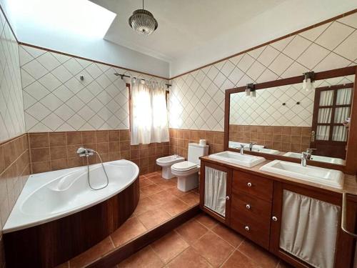a bathroom with a tub and two sinks and a toilet at Private villa with pool in the mountains in Pájara
