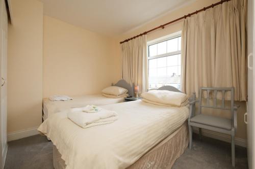 two beds in a room with a window and a chair at Four Seasons B&B in Galway