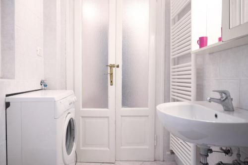 a white bathroom with a washing machine and a sink at Casina modesta in Somma Lombardo