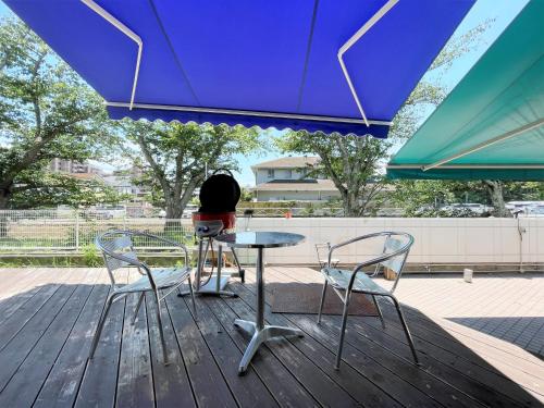 a person sitting at a table under a blue umbrella at 365BASE outdoor hostel in Hamamatsu