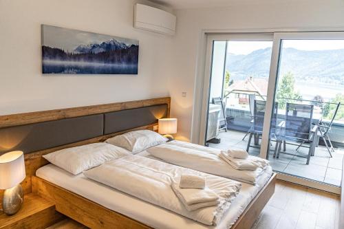 a bedroom with a bed and a view of a balcony at Top 9 Alpe Maritima - Lakeview Apartment mit Bergkulisse in Annenheim