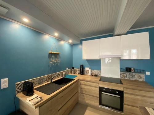 a kitchen with blue walls and white cabinets and a sink at La belle vue in Accolay