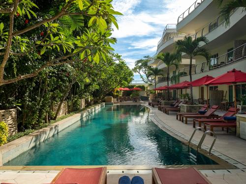 una piscina junto a un hotel con mesas y sillas en Anantara Vacation Club Legian en Legian