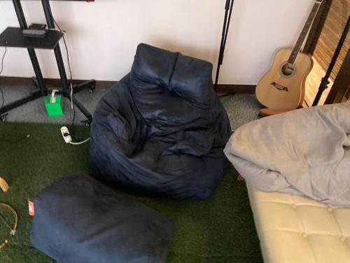 a room with a bean bag chair and a guitar at Hero Guest Room in Busan