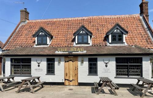 a white building with two picnic tables in front of it at The Stag, Oak Room in Salhouse