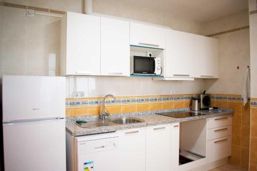 een keuken met witte kasten, een wastafel en een koelkast bij Vacation rental Fuengirola in Fuengirola