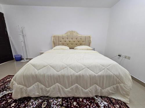 um quarto com uma cama grande e um edredão branco em استراحة المسافر em Al Ain
