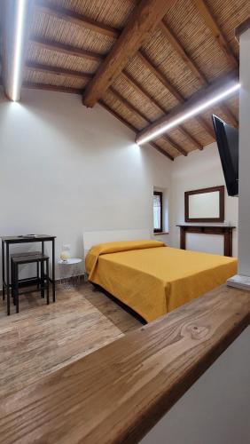 a bedroom with a yellow bed and a desk at Luciae Domus in Roccascalegna