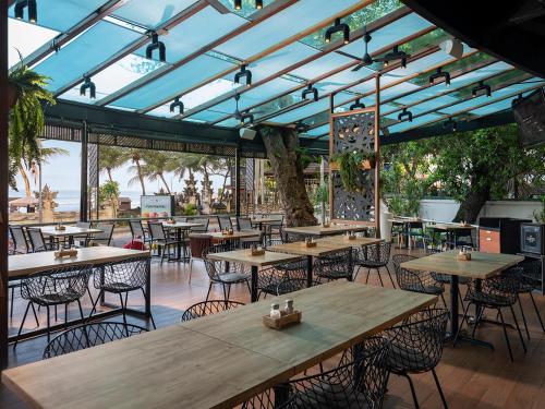 un restaurante con mesas y sillas de madera y techos azules en Anantara Vacation Club Legian, en Legian