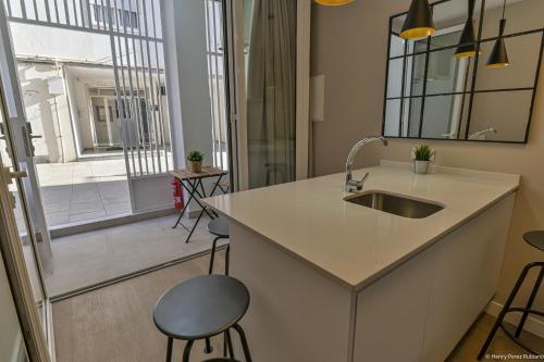 a kitchen with a sink and a counter with stools at Apartamentos Bela in Cangas de Morrazo