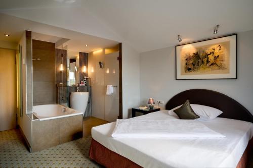 a hotel room with a bed and a bath tub at Hotel Lechnerhof Unterföhring in Munich