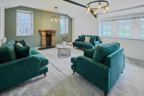 a living room with two green couches and a fireplace at Stay House - Rural Retreat in Kepwick