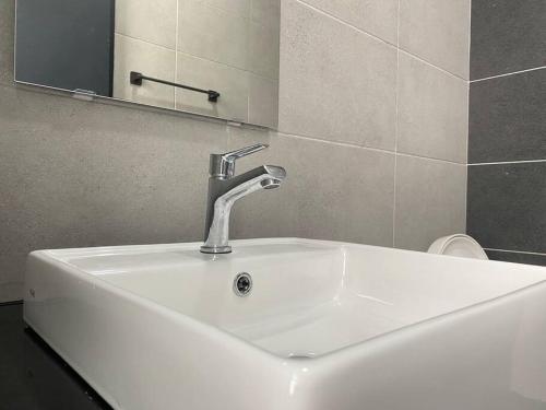 La salle de bains est pourvue d'un lavabo blanc et d'un miroir. dans l'établissement Urban Suites Georgetown, Penang, à Jelutong