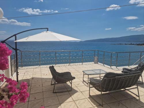 een patio met stoelen, een tafel en een parasol bij Sea Front Villa near Athens in Isthmia