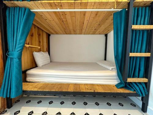 a bunk bed in a room with blue curtains at Vika Homestay in Ho Chi Minh City