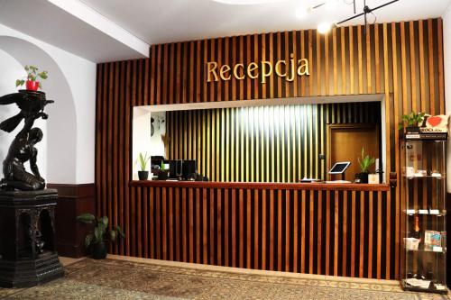 a hotel lobby with a reception desk and a sign on the wall at Hotel Lothus in Wrocław