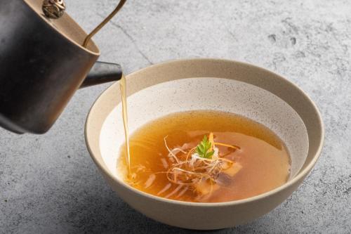 a bowl of noodle soup being poured from a pot at CHAO Sanlitun Beijing in Beijing