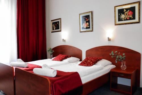 two beds in a hotel room with red curtains at Hotel Lothus in Wrocław