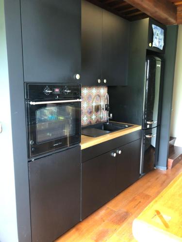 a black kitchen with a stove and a sink at Záhradný domček in Levoča