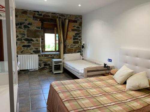 1 dormitorio con 1 cama en una habitación con una pared de piedra en Agroturismo Gure Naia, en Carranza