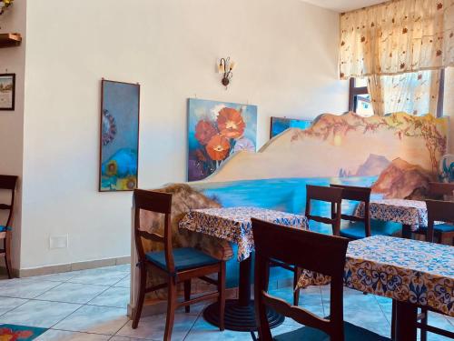 un comedor con mesas, sillas y pinturas en la pared en La Cascina Camere, en Agerola