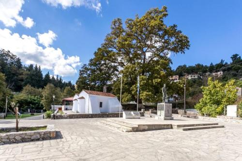 a park with a white building and a tree at Ifigenia Theriso Village in Thérison