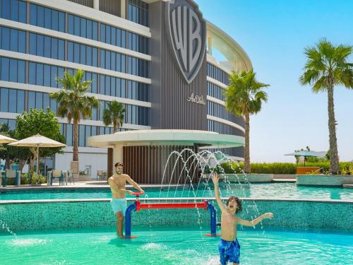 a man and a boy playing in the water in a pool at The WB Abu Dhabi, Curio Collection By Hilton in Abu Dhabi
