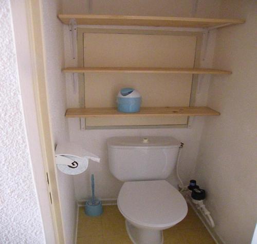 a bathroom with a white toilet with wooden shelves at Au Coeur De La Station in Les Deux Alpes
