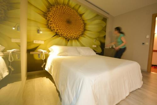 a bedroom with a large sunflower painting on the wall at Hotel Jucamar in Cangas de Morrazo