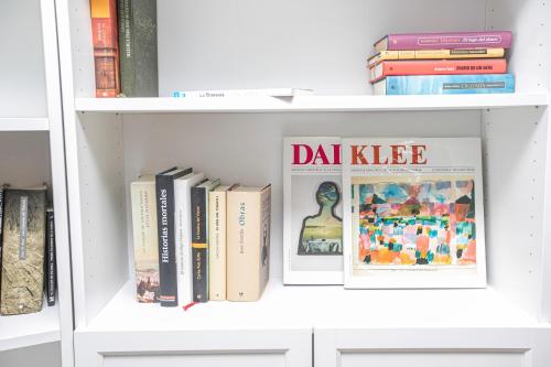 a white book shelf with books and magazines at Albergue A Fabrica in Santiago de Compostela