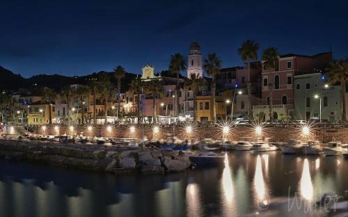 a city at night with boats in the water at Nonna Sere Home in Riva Ligure