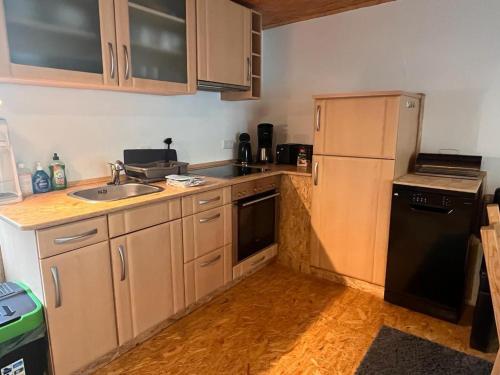 a kitchen with wooden cabinets and a sink and a refrigerator at Ferienhäuschen / Ferienwohnung Fam. Duen in Bad Wildungen