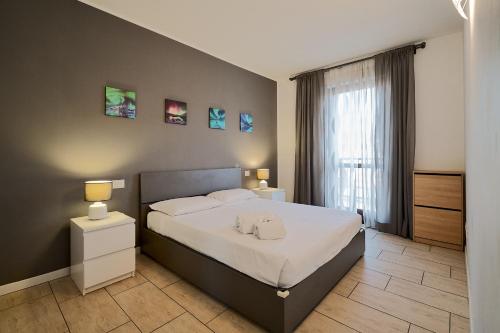 a bedroom with a bed with white sheets and a window at Xenia Apartments - New and Bright Urban Housing in Milan