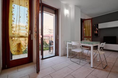a room with a table and chairs and a balcony at Xenia Apartments - New and Bright Urban Housing in Milan