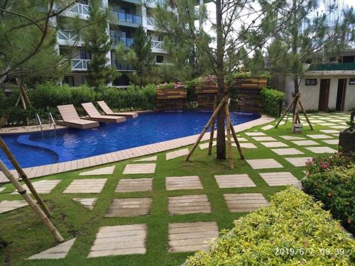 a swimming pool with lounge chairs in a yard at Pine Suites JR Studio, a Serene & Relaxing place in Tagaytay