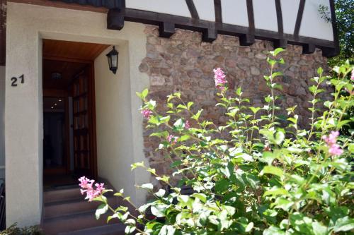 a house with a stone wall and a plant with pink flowers at Ferienwohnung Sester in Gengenbach