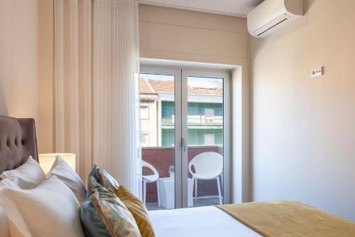 1 dormitorio con 1 cama y ventana con balcón en Liberdade Home Stay - Minho's Guest en Braga