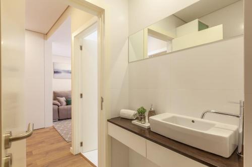 La salle de bains blanche est pourvue d'un lavabo et d'un miroir. dans l'établissement Liberdade Home Stay - Minho's Guest, à Braga